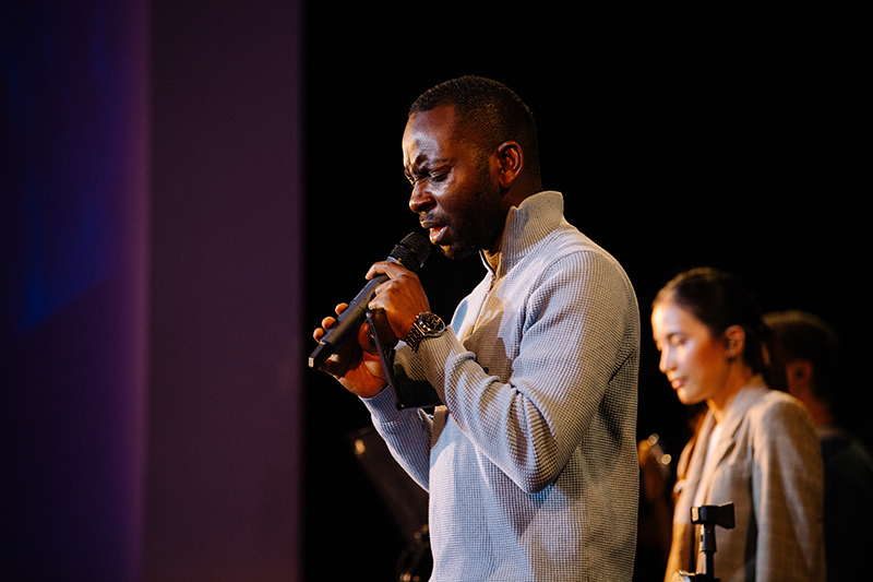 man holding microphone, singing with his eyes closed